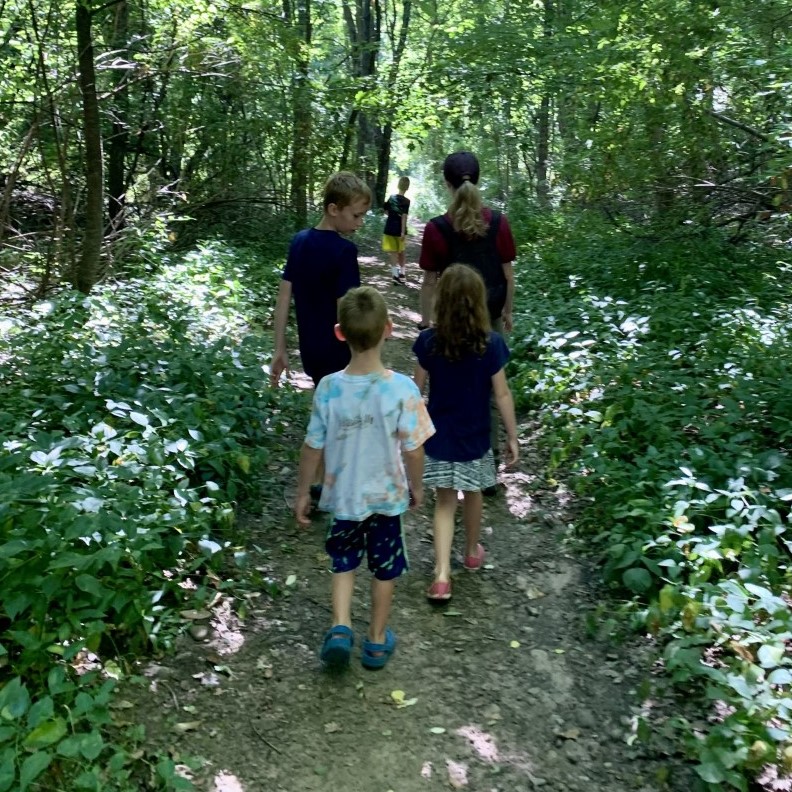 kids and adults walking a path in the woods.