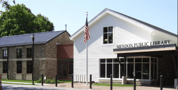 Flagpole entrance of the Mendon Public Library showing both architectural halves of the library building.