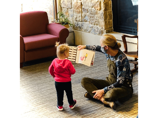 A toddler approaches the reader during story time.