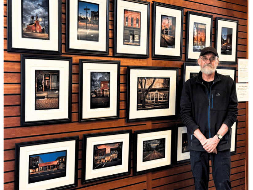 Paul Bergwall poses in front of his photography display at Mendon Public Library.